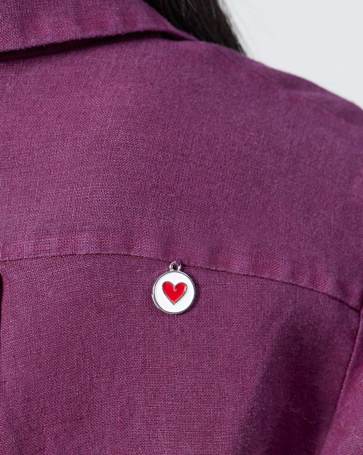 Close-up of a red-heart charm on plum Mati linen.
