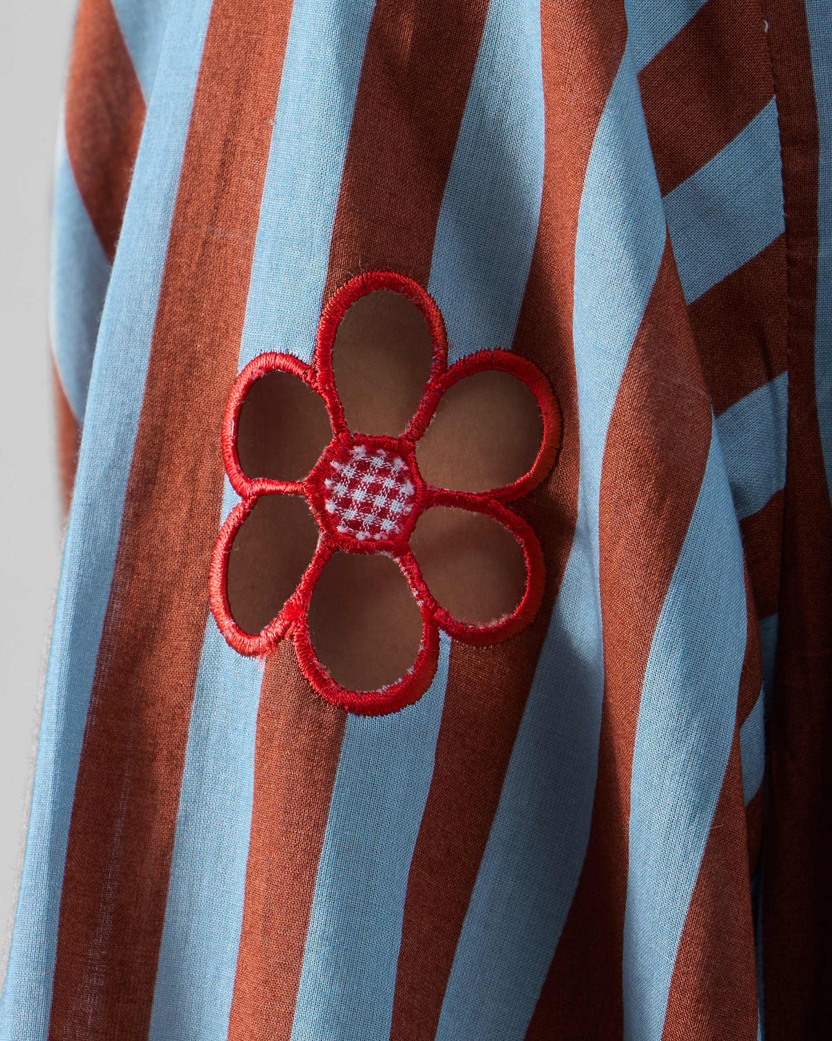 Close-up of a red flower cutout on a blue and brown striped Summer Tea dress.
