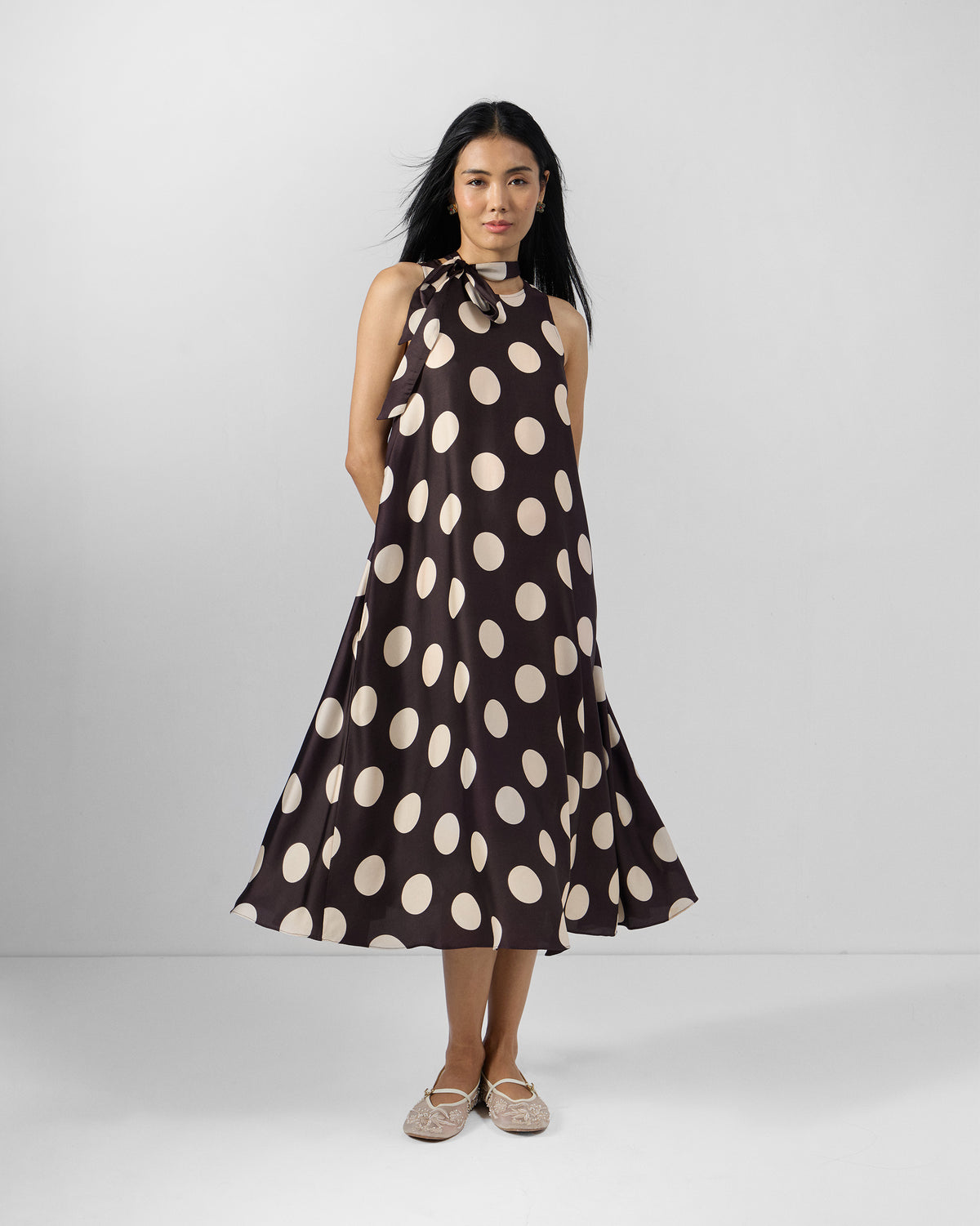 Person wearing a brown Kinaar Dress with ivory polka dots and a flared midi skirt.