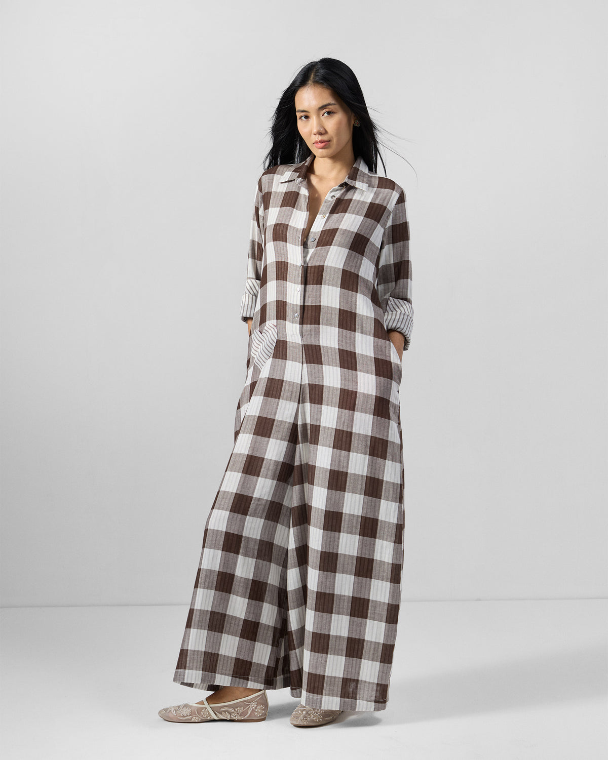Person wearing a brown and ivory check cotton jumpsuit with shirt collar and wide legs.