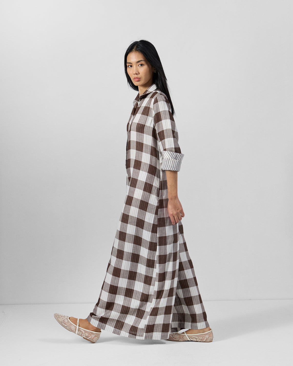 Side view of a brown and ivory check jumpsuit showing full-length wide legs.