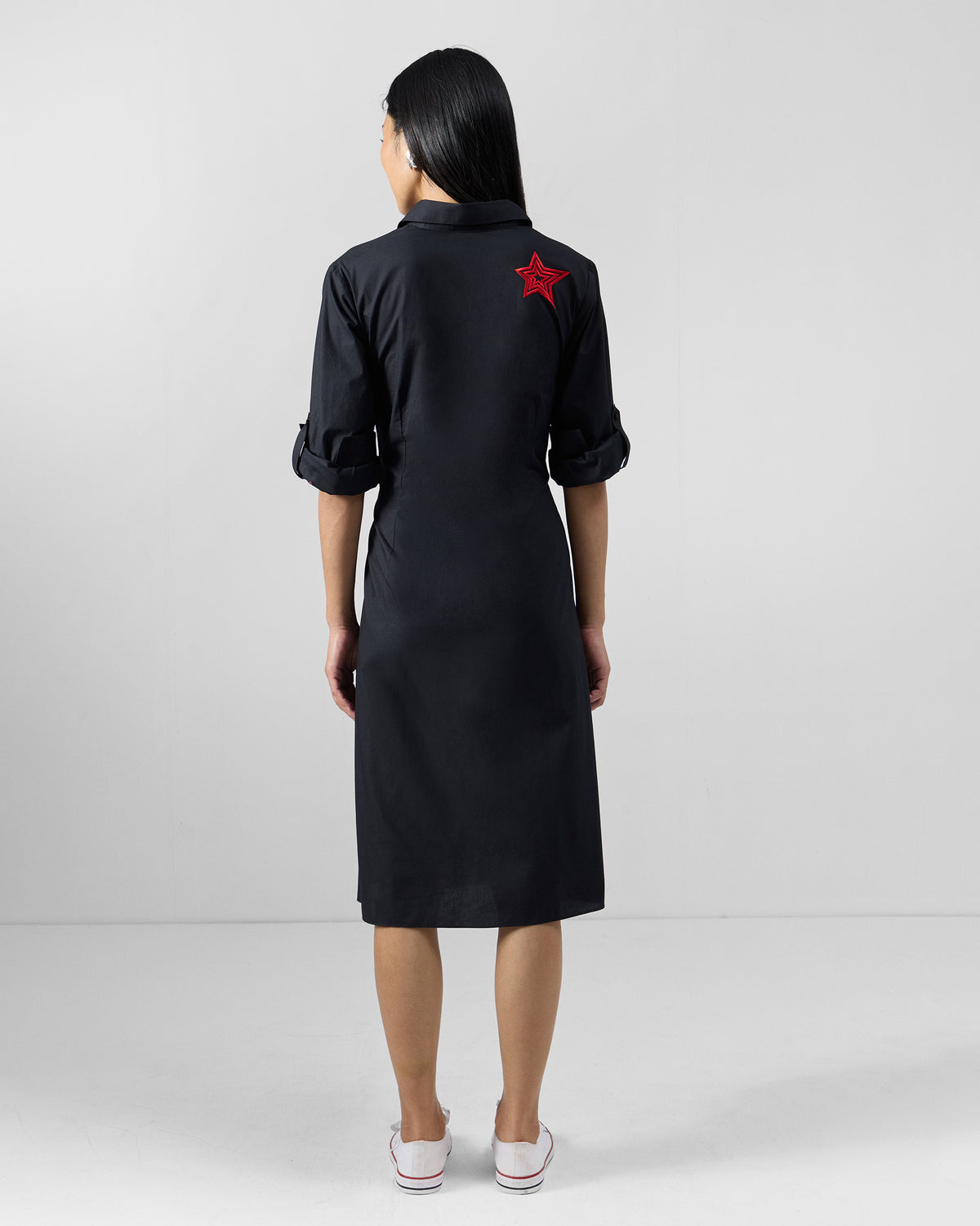 Back of a black shirt dress with a red embroidered star.