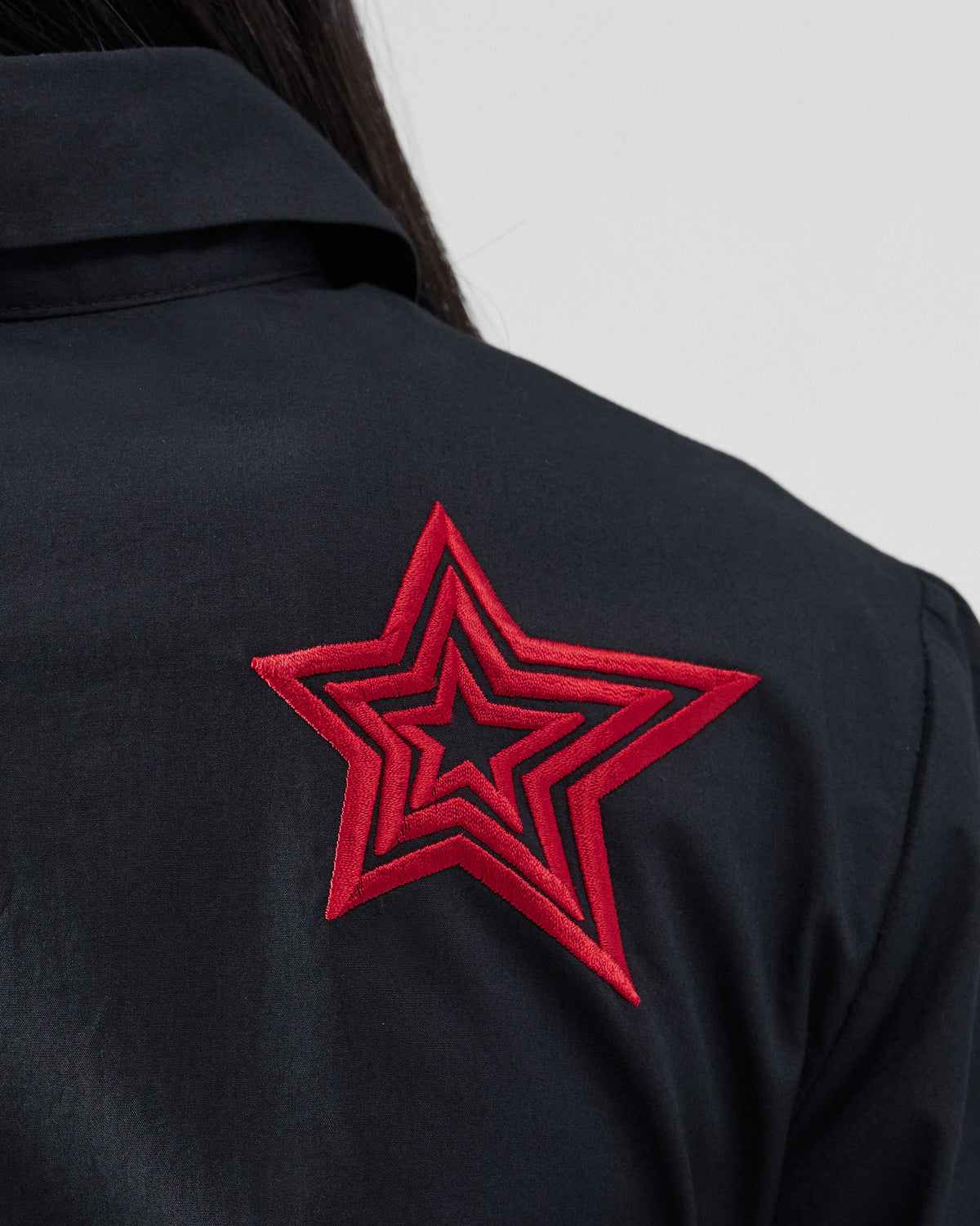 Close-up of a black dress with nested red embroidered stars.