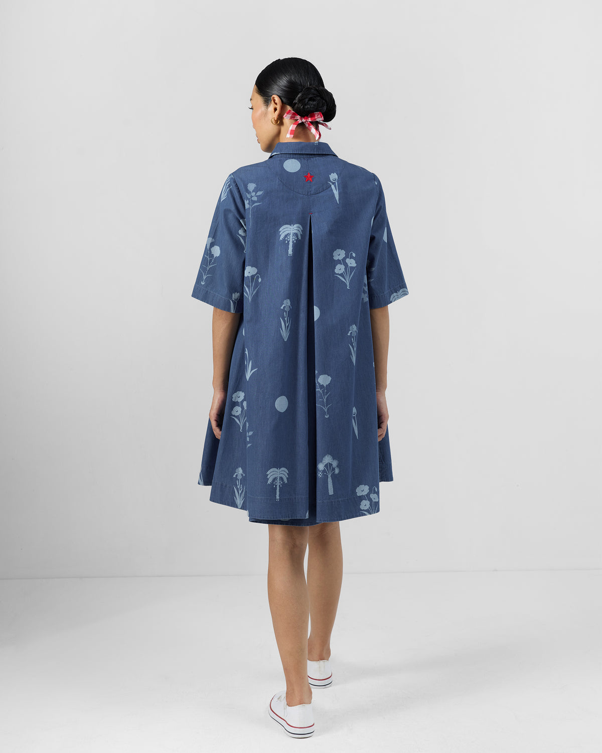 Back of a blue Happy Heart dress with a yoke pleat and floral print.