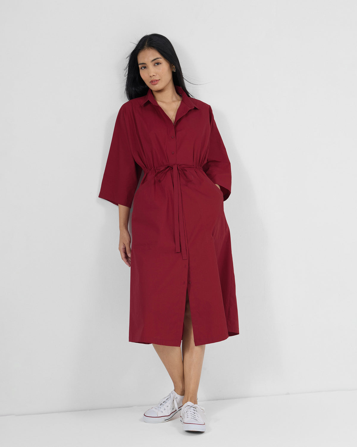 Person wearing a red Nomad shirt dress with a matching waist tie.