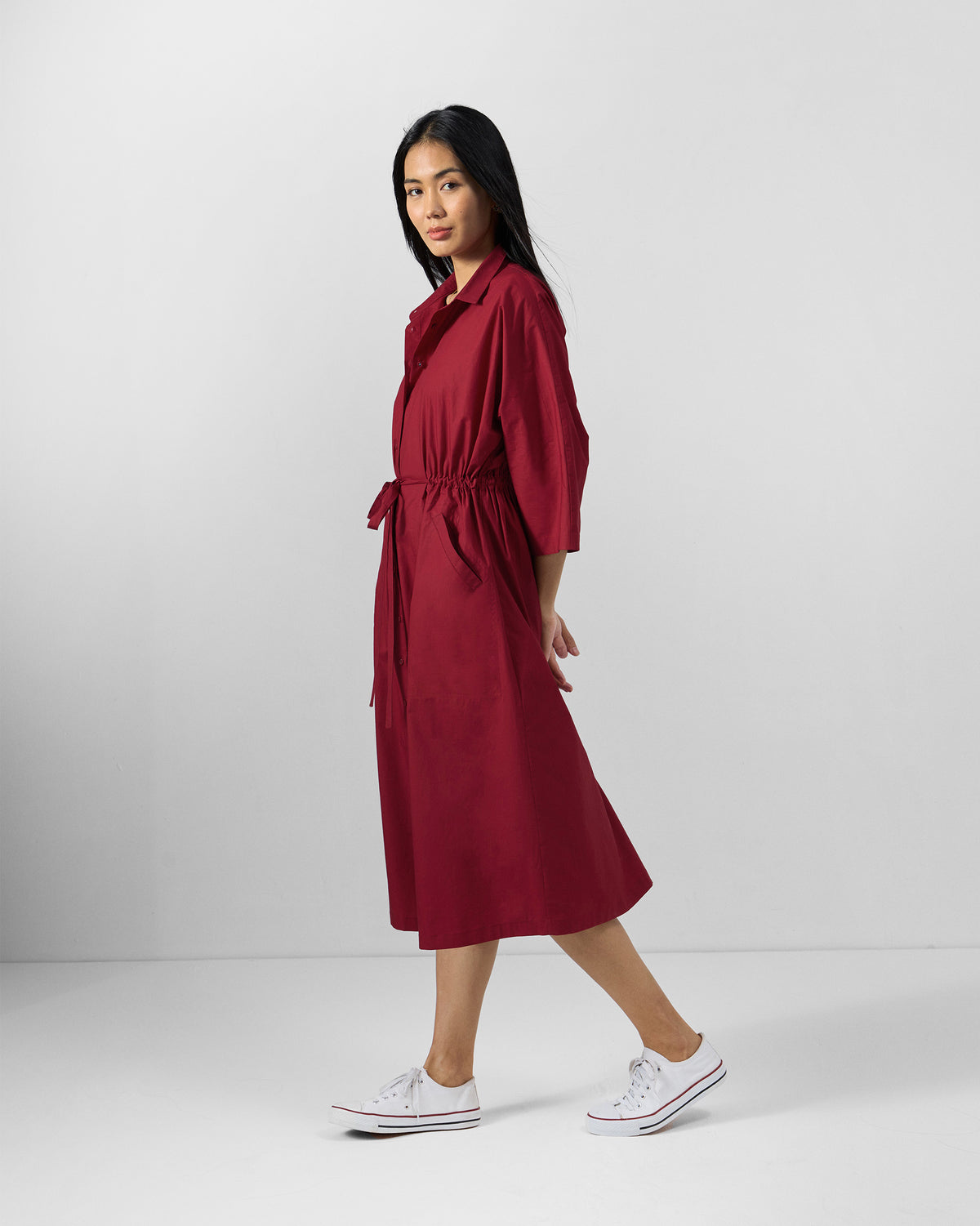 Side view of a red Nomad shirt dress with a waist tie.