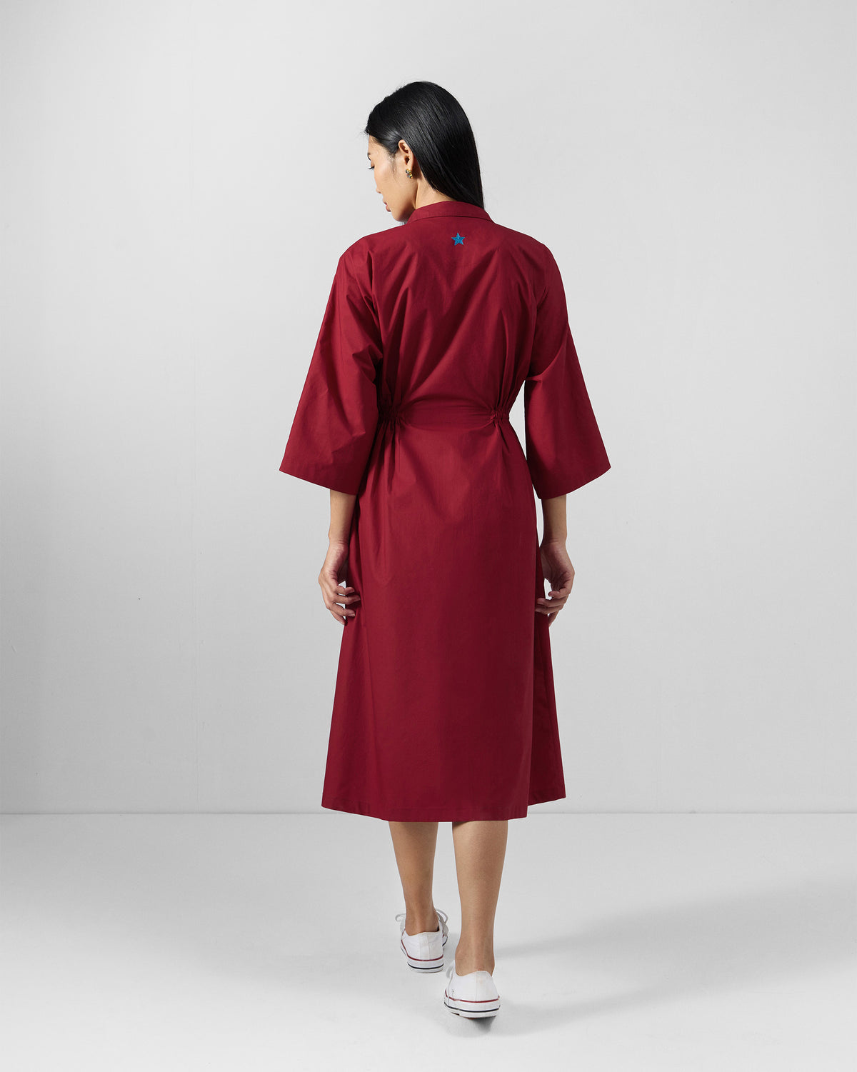 Back of a red Nomad dress with a blue embroidered star.