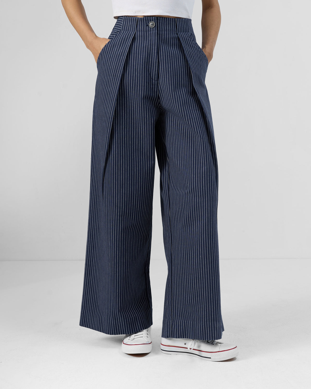 Person wearing navy striped Costa pants with front pleats and a button fly.