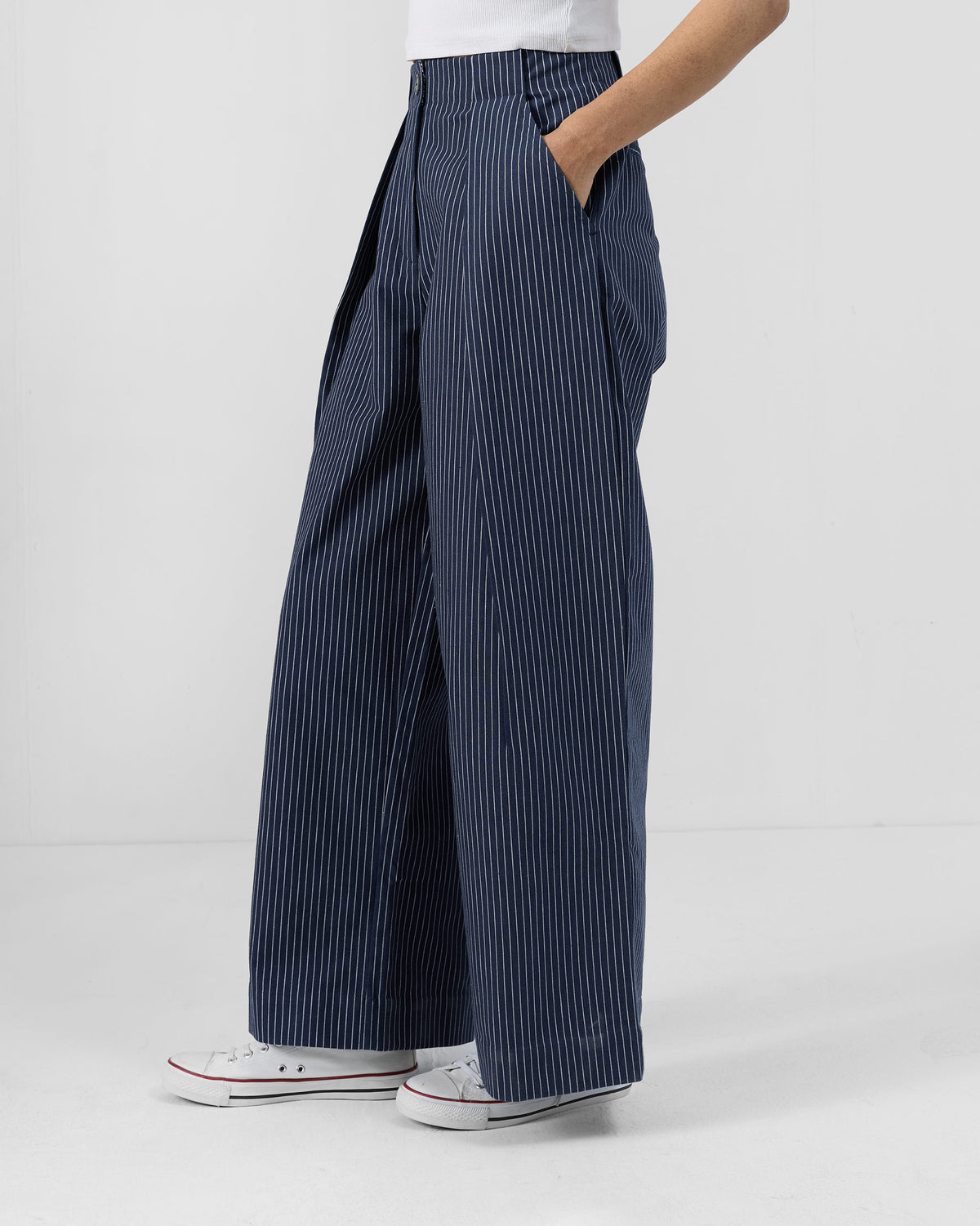 Person wearing navy striped Costa pants with a hand in the side pocket.