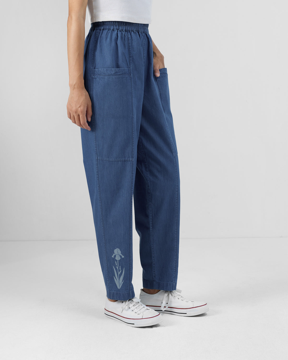 Side view of blue Kaiteki Pants with a patch pocket and floral print near the hem.