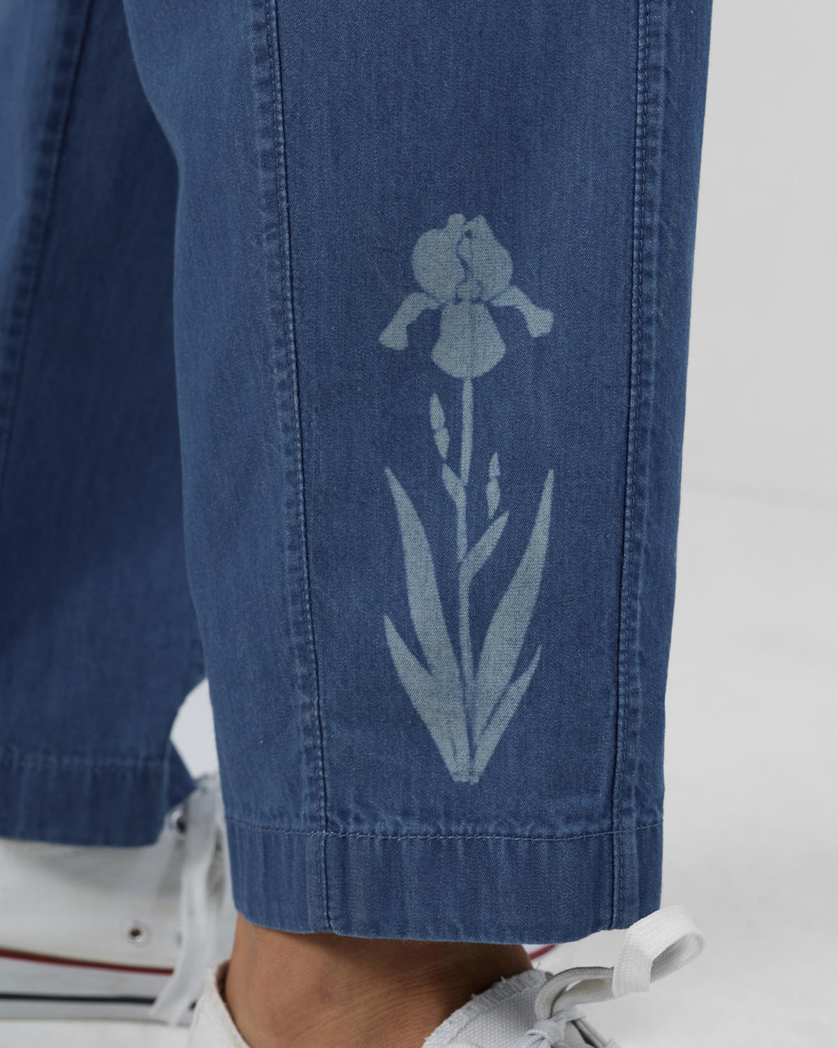 Close-up of a pale floral print near the hem of blue Kaiteki Pants.