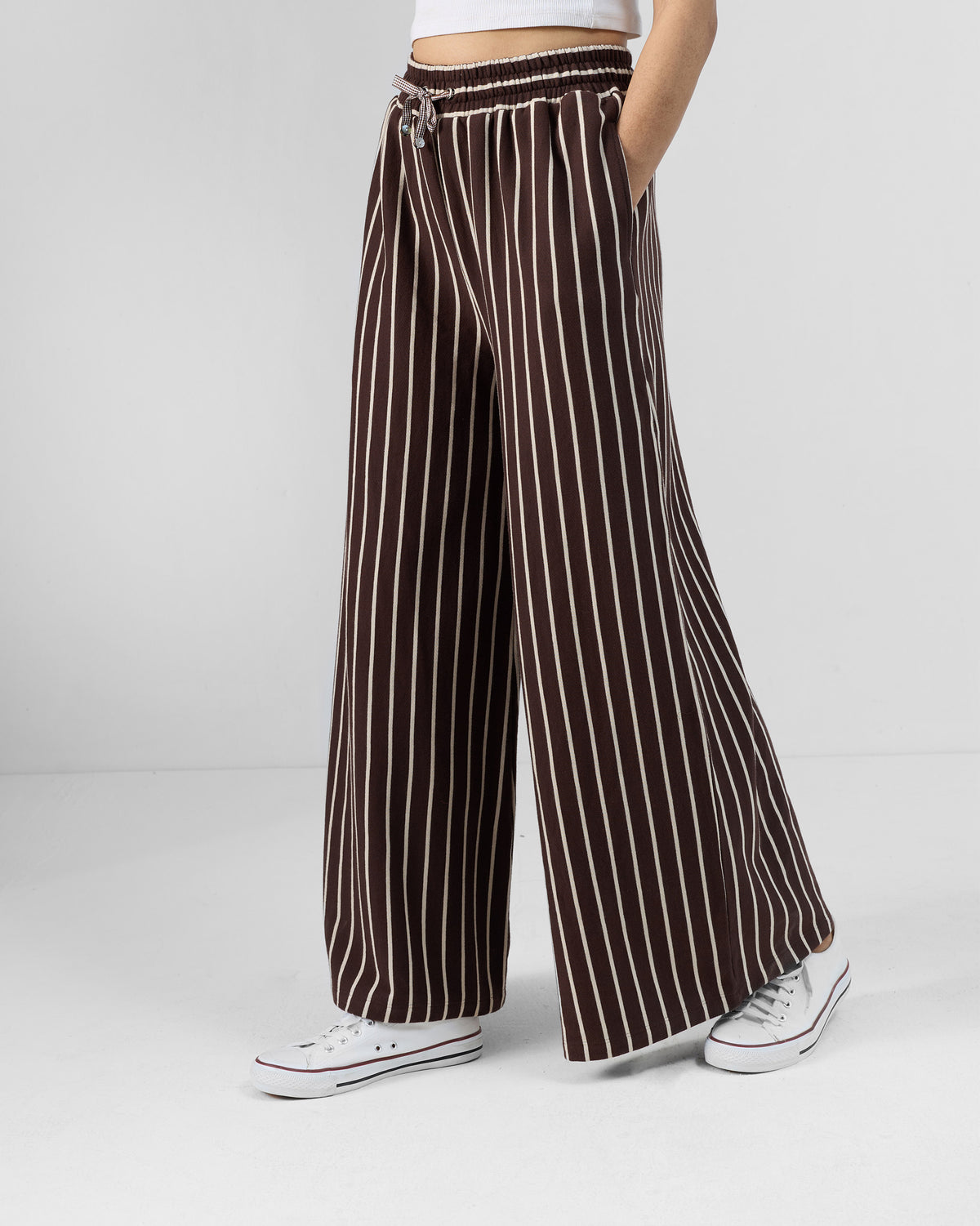 Side view of brown and ivory Nova pants showing a side pocket and wide-leg drape.