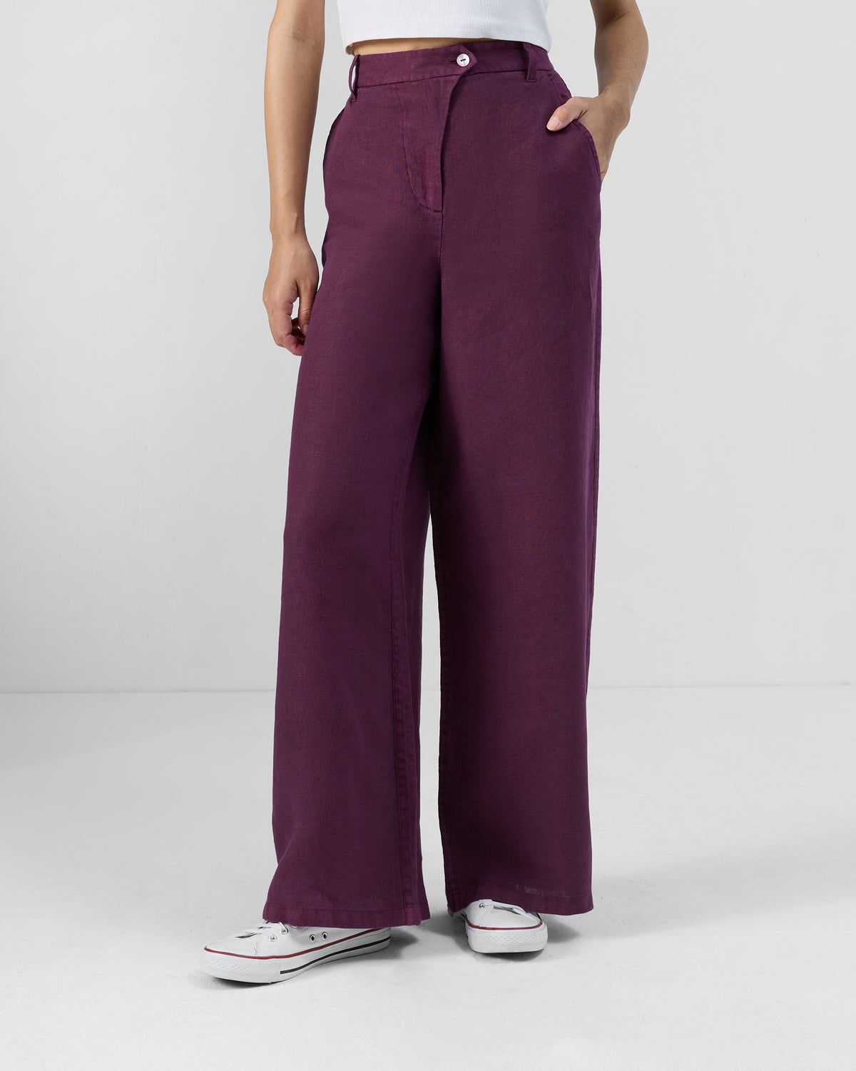 Person wearing plum linen Aven pants with a white waist button.