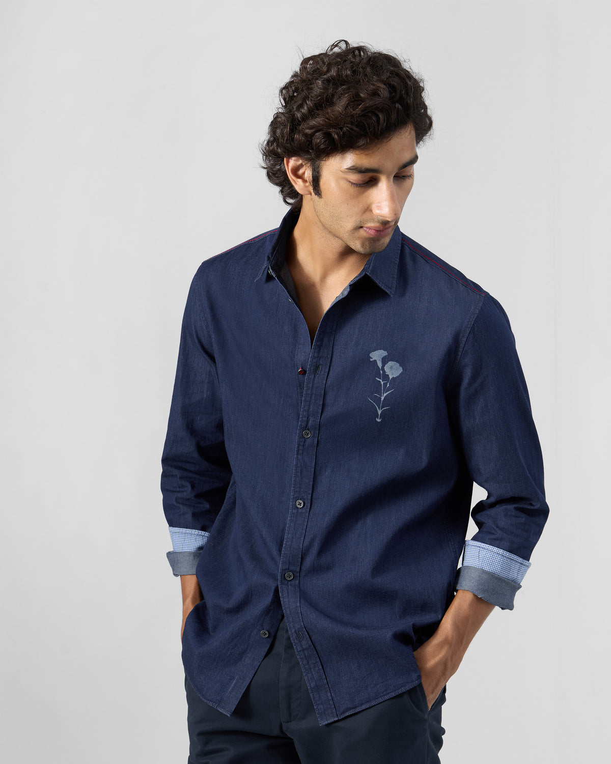 Person wearing an indigo denim Classic shirt with a floral chest print.