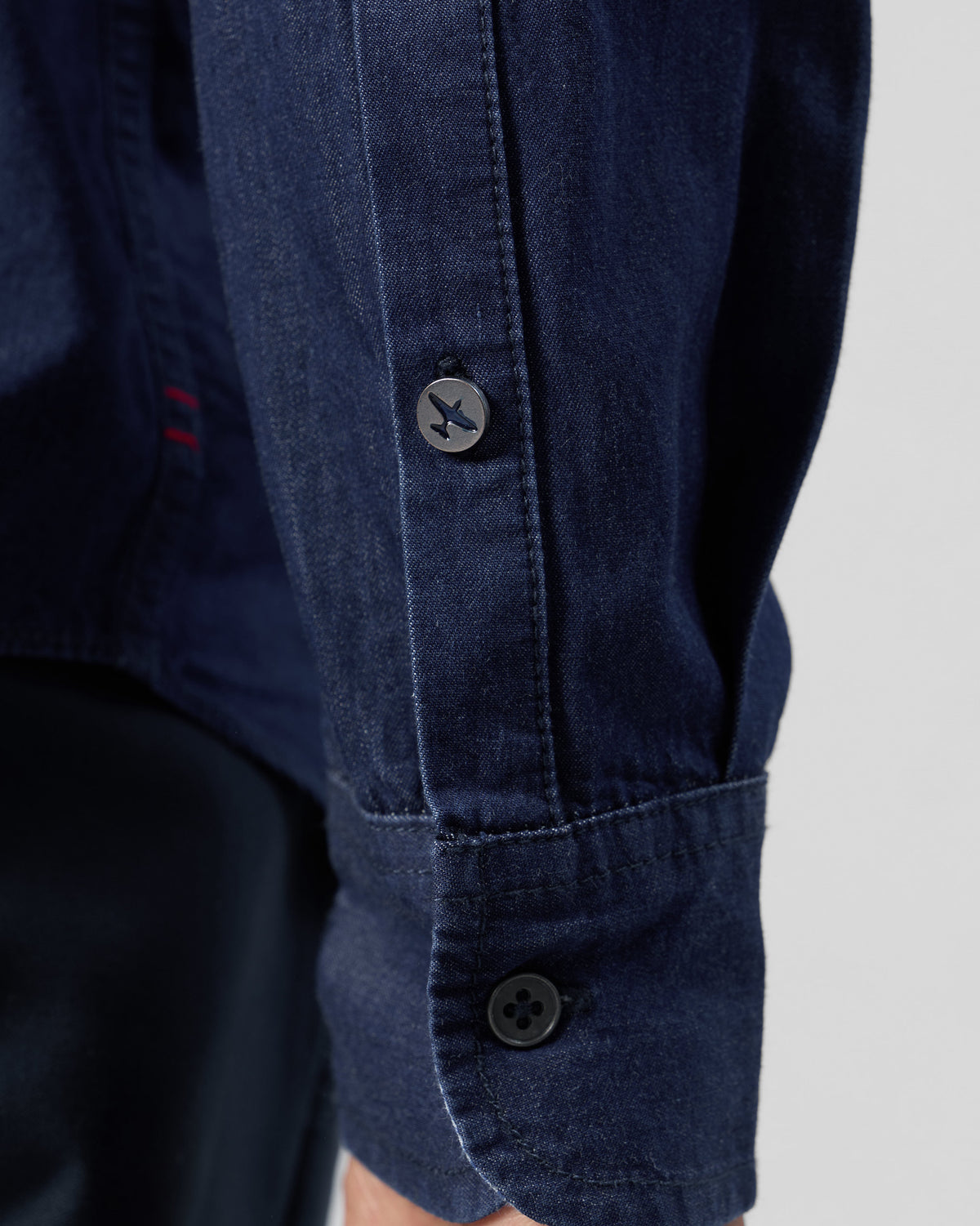 Close-up of an indigo denim Classic shirt cuff with a plane button.