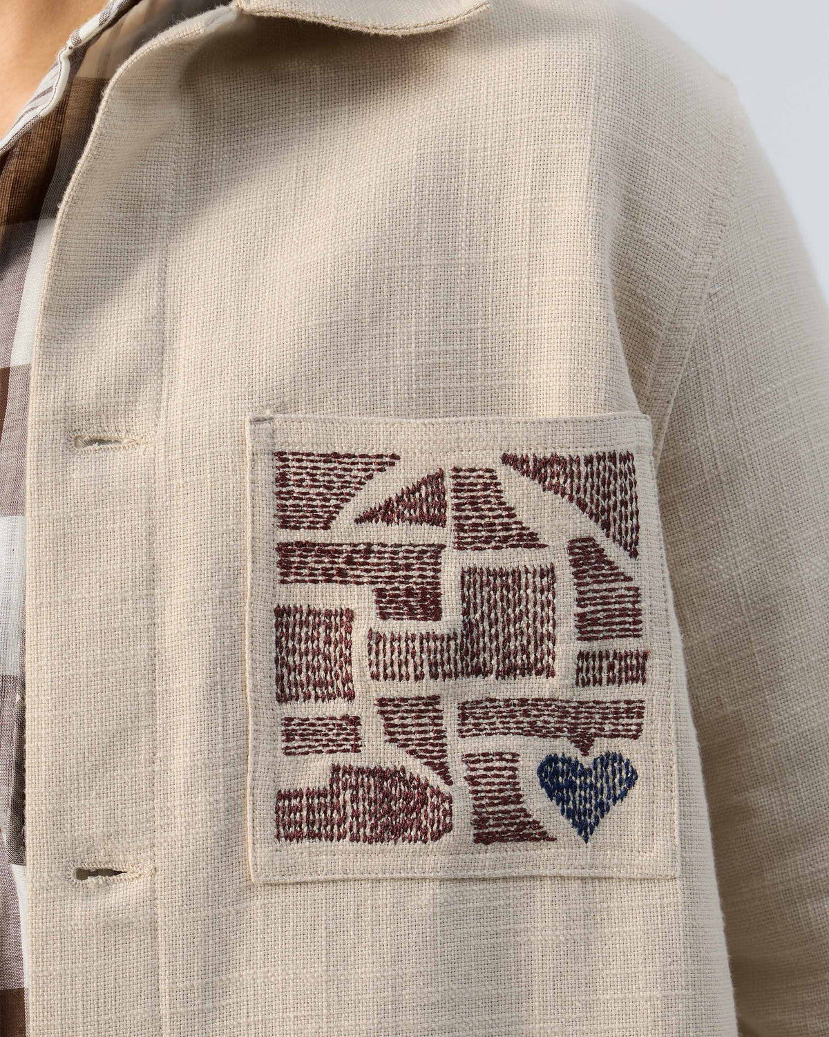 Close-up of geometric embroidery and a blue heart on a Dune shacket pocket.
