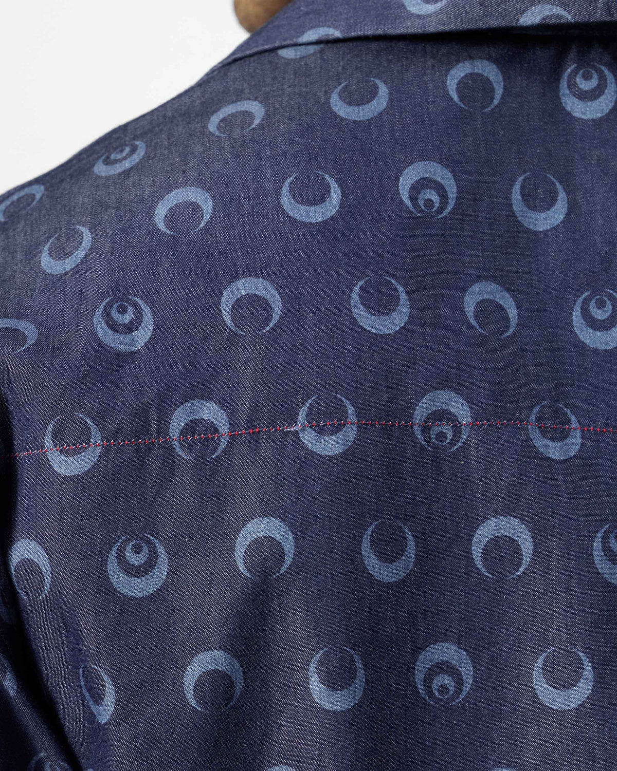 Close-up of moon print and red stitching on an indigo Yamuna kurta shirt.
