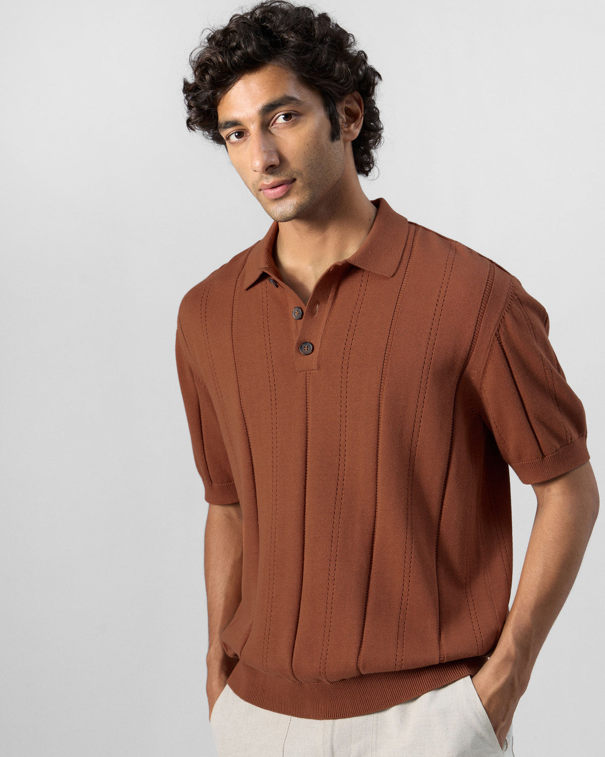 Person wearing a rust Abeer polo with self-stripe knit.