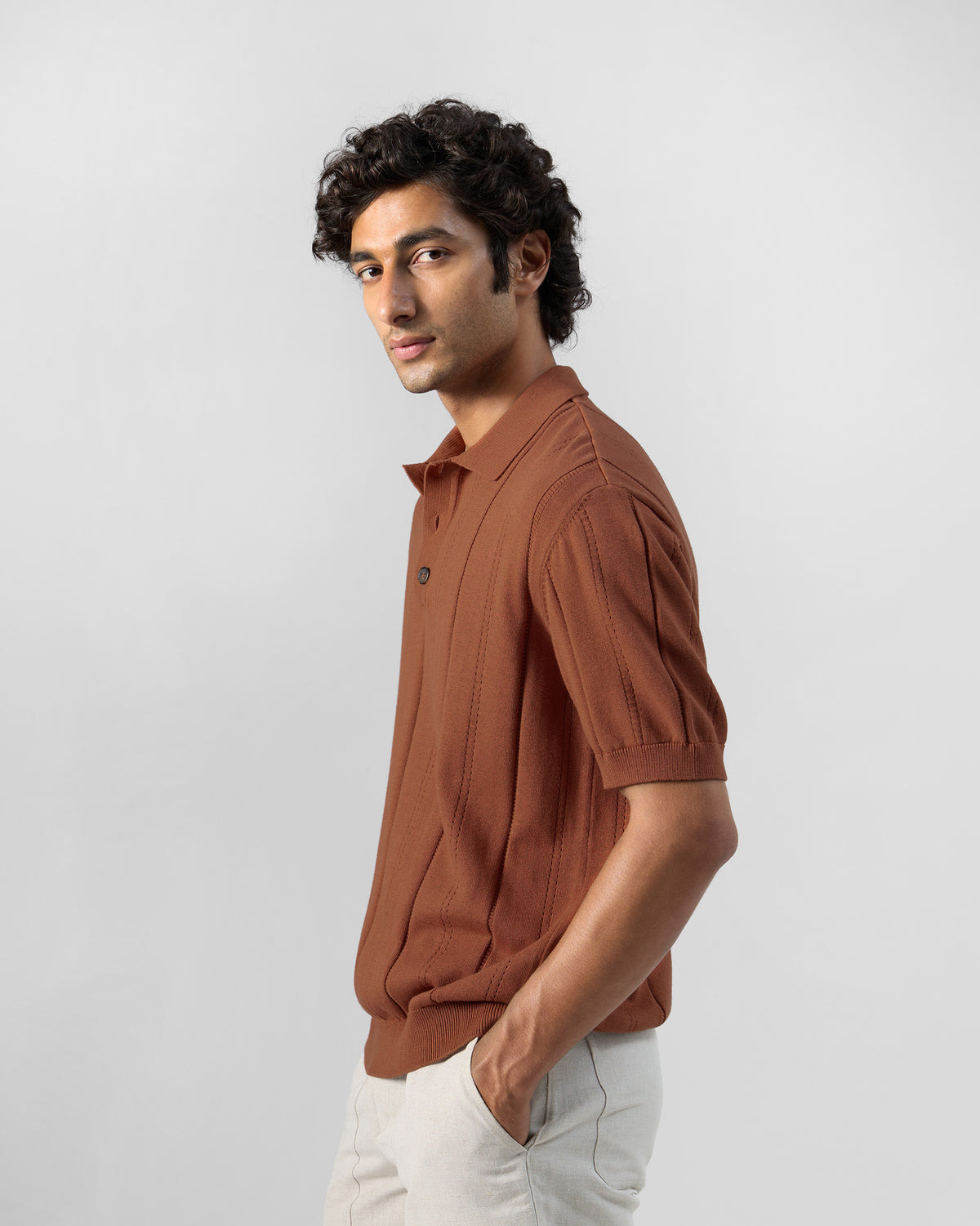 Side view of a rust Abeer polo with self-stripe knit.
