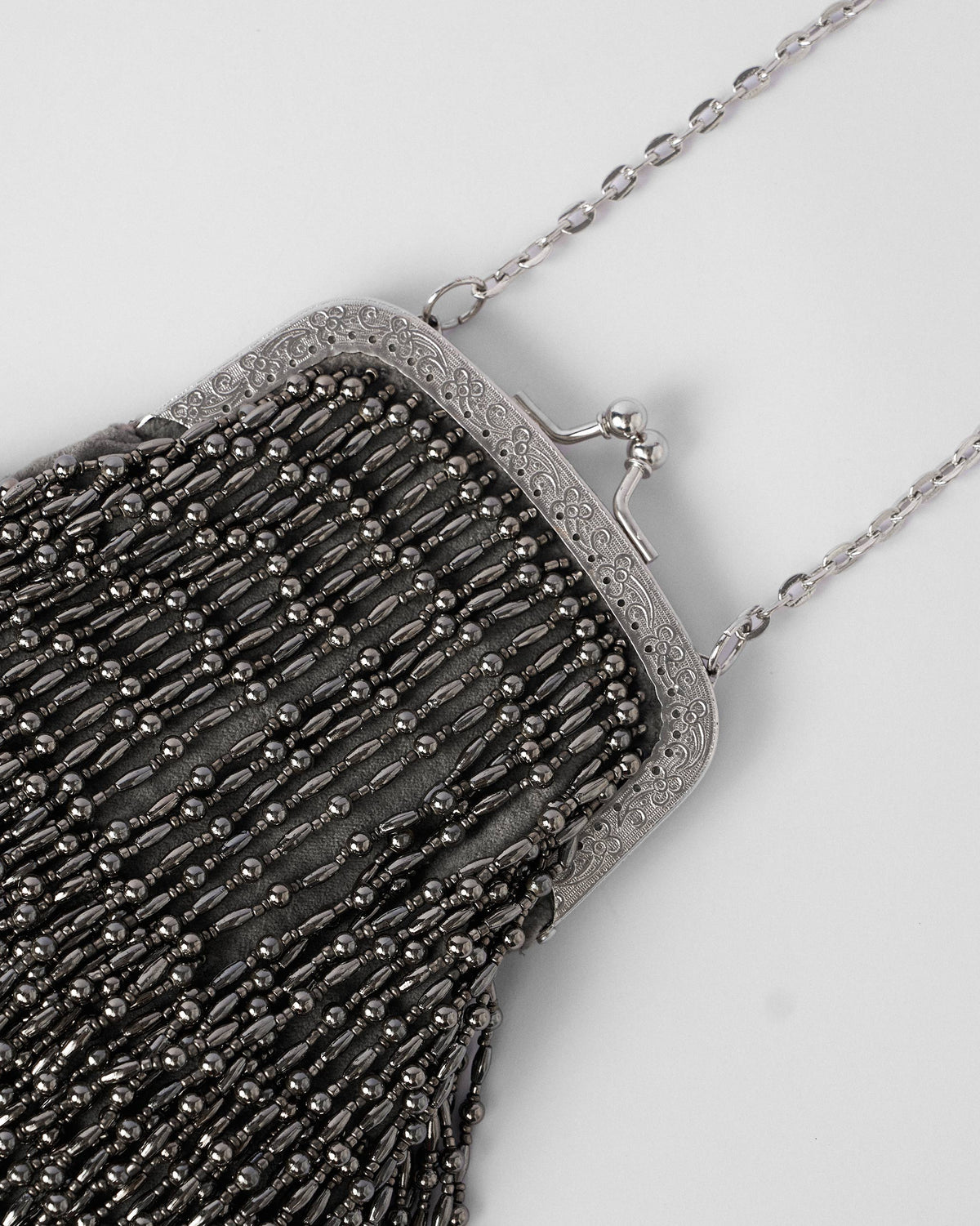Close-up of silver bead strands and an engraved kiss-lock frame on the clutch.