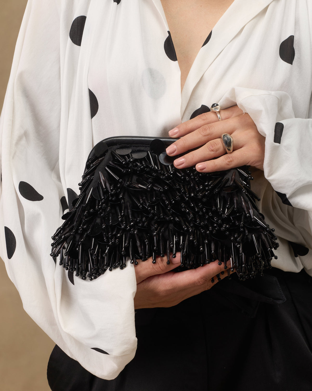 Person holding a black Starry Night Clutch covered in beaded fringe.