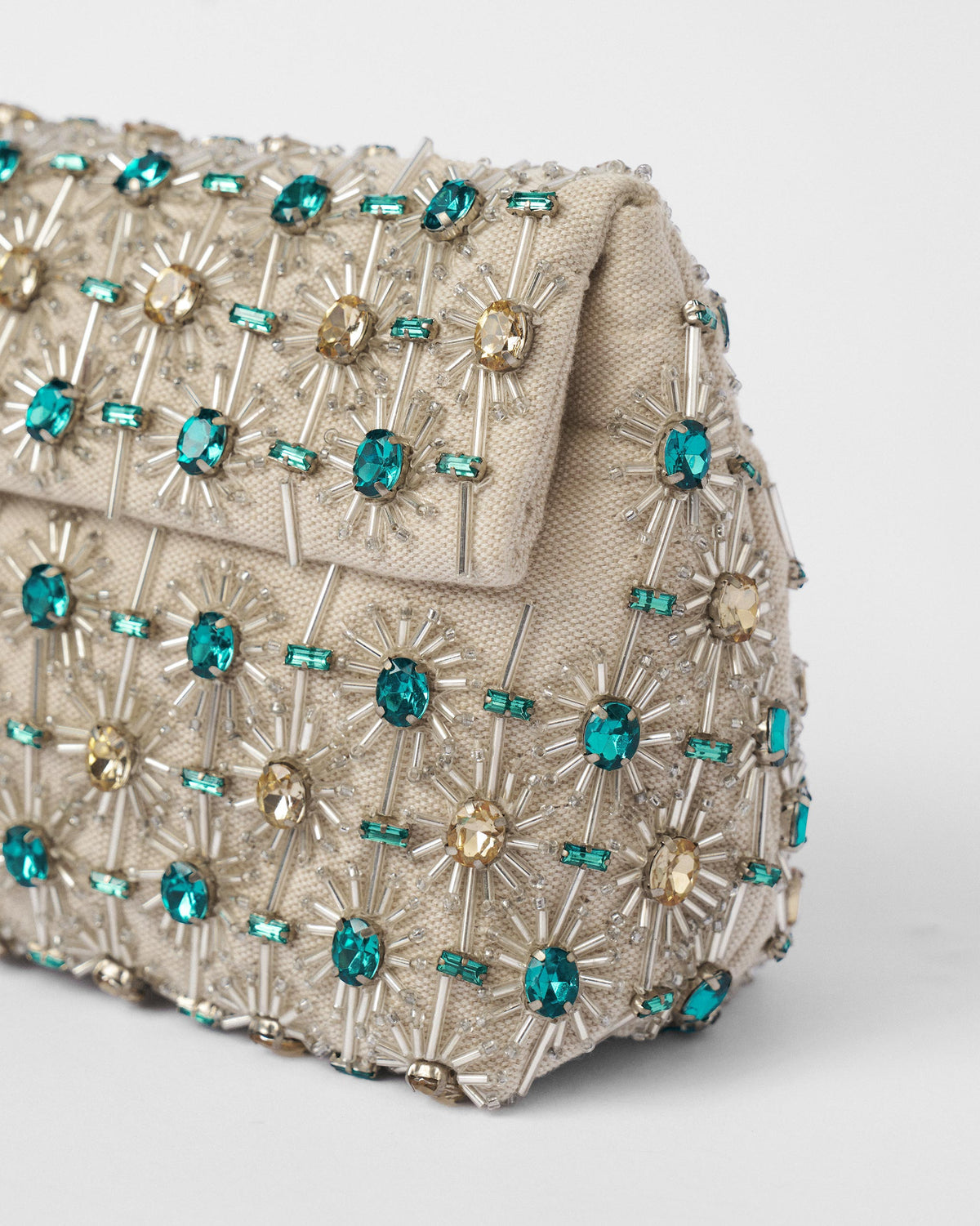 Close-up of the teal gem beadwork on an ivory Noor Clutch.