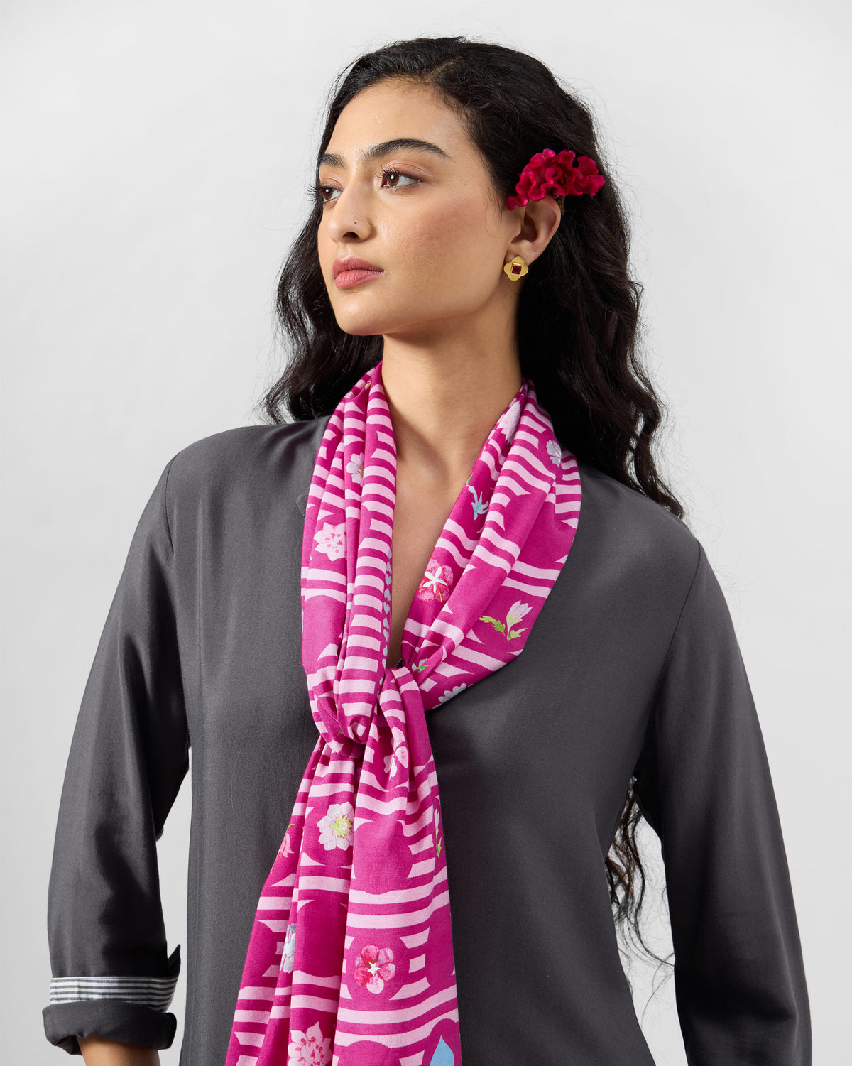 Person wearing a pink River Blooms scarf with white stripes and flower motifs.
