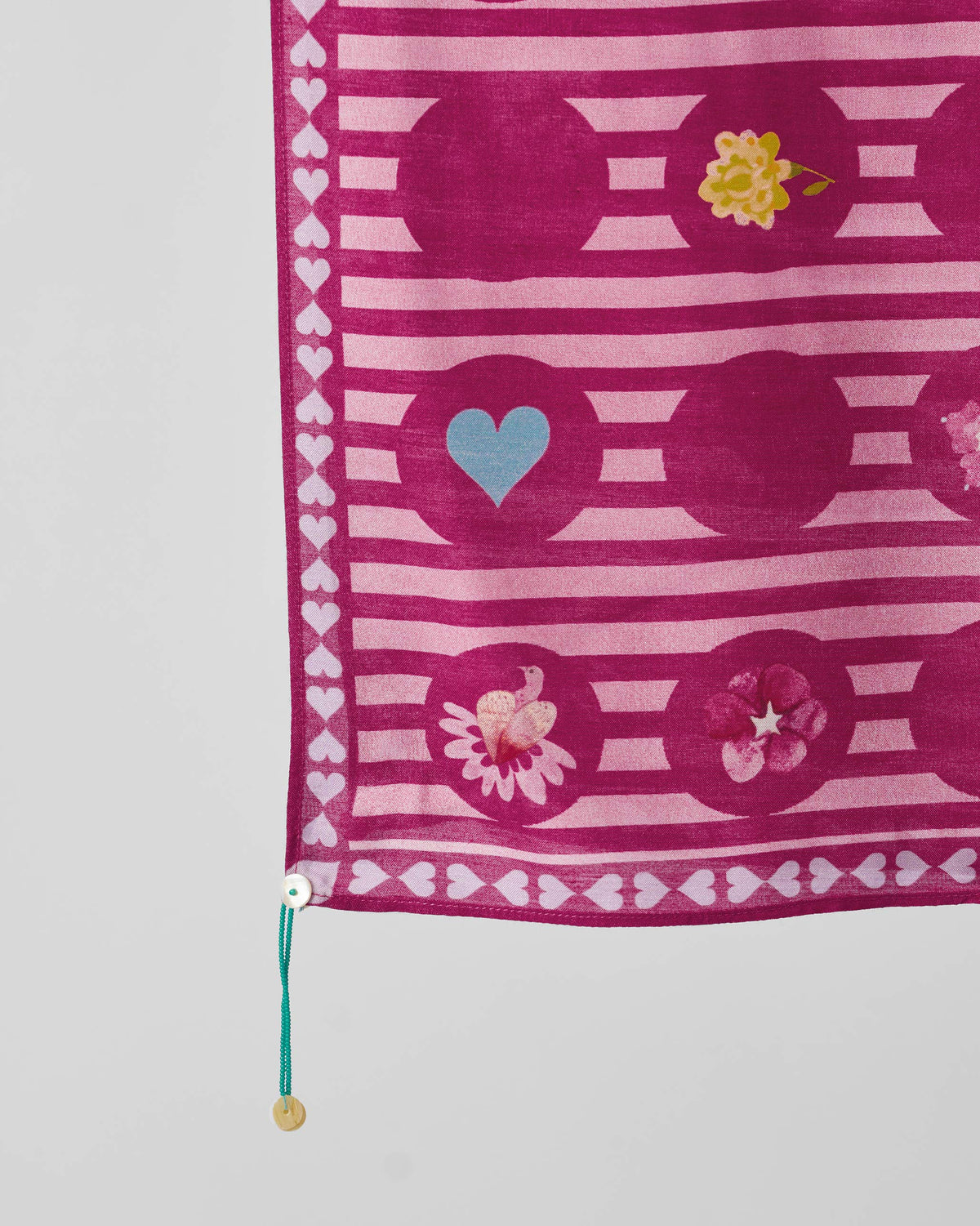 Close-up of River Blooms scarf showing a blue heart and flower motifs.