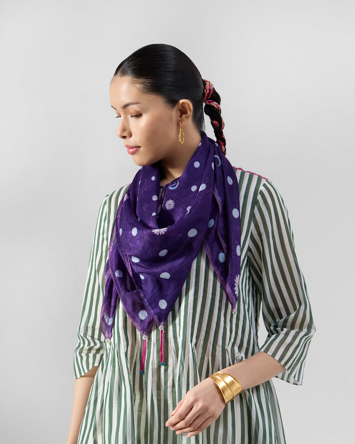 Purple polka scarf draped around a person's neck over a striped dress.