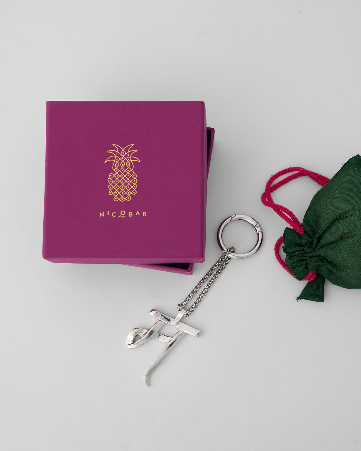 Silver Alphabet M bag charm with a magenta Nicobar gift box.