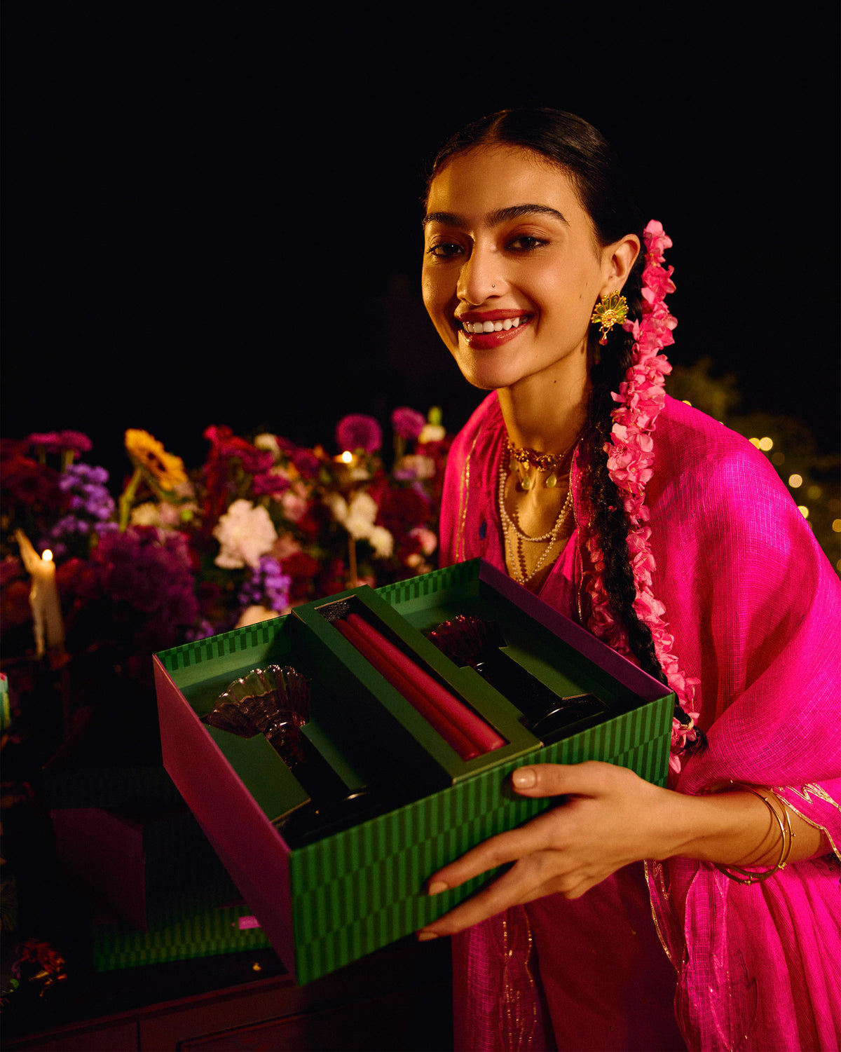 Person holding an open gift box with Ember candle holders and taper candles inside.