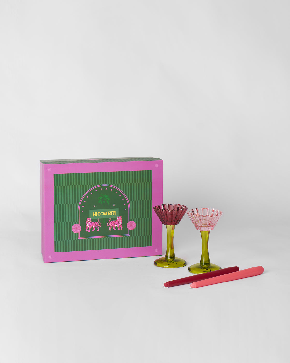 Ember candle holders and taper candles set beside their pink and green gift box.