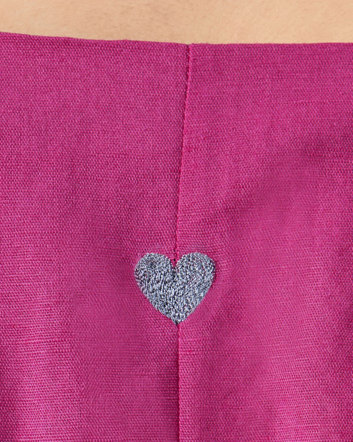Close-up of a silver heart embroidered on a berry pink Nihra Kaftan.