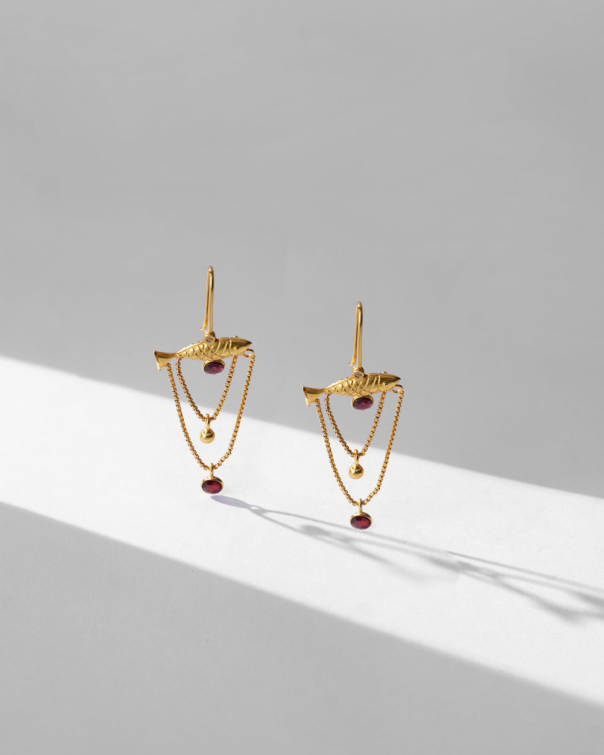 Pair of gold Maase fish earrings showing layered chains.