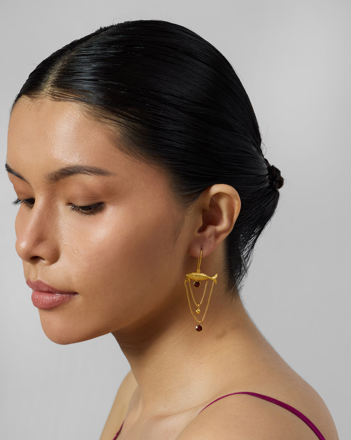 Side profile of a gold Maase fish earring with chain loops.
