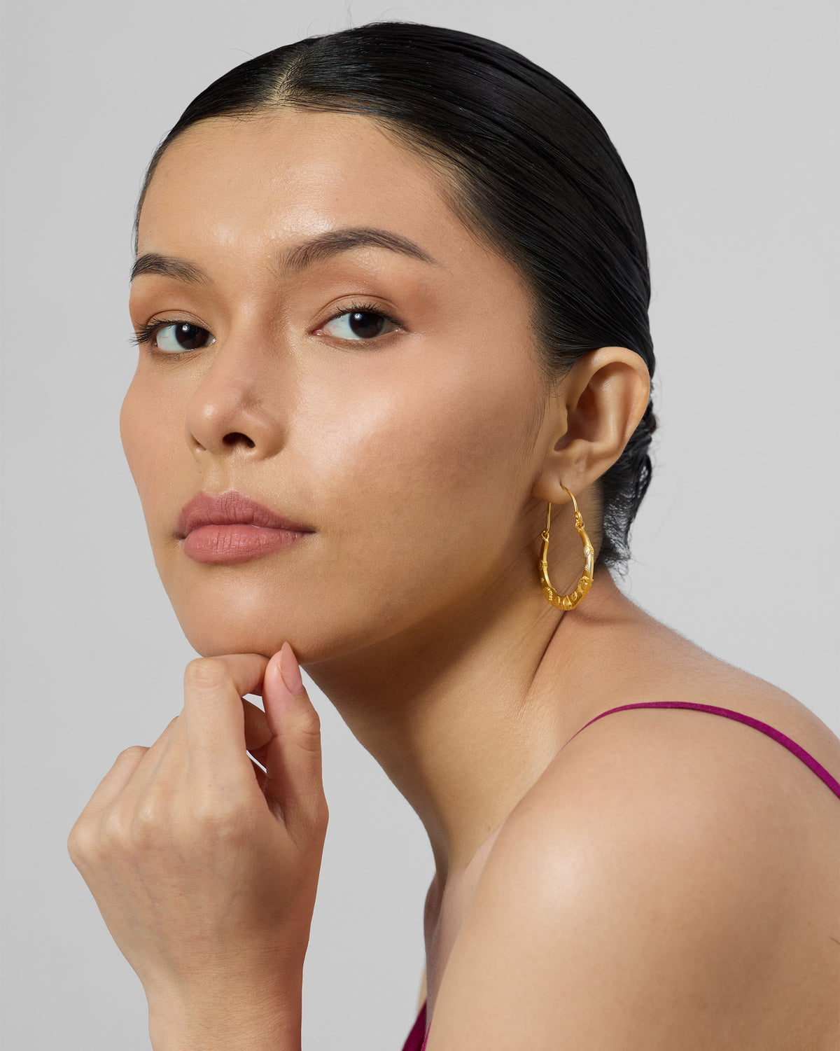 Person wearing a gold ellora bali with embossed texture.