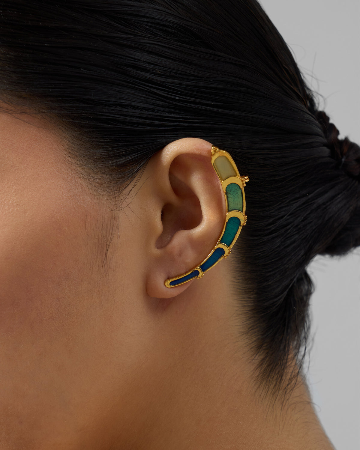Side profile of a gold Rising Moon enamel ear climber on a person.