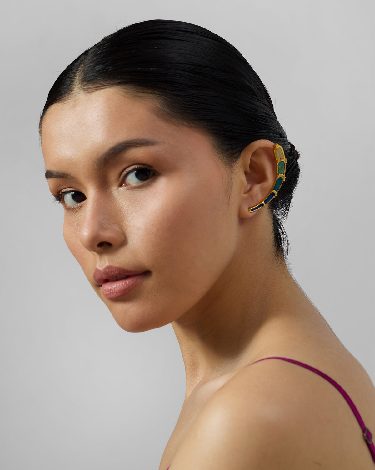 Person wearing a gold Rising Moon enamel ear climber.