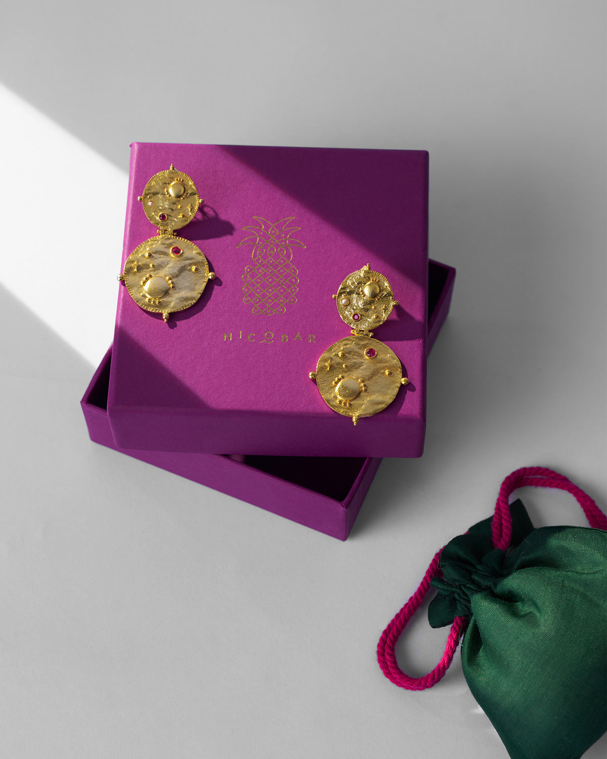 Gold Rishi disc earrings on a purple Nicobar gift box.