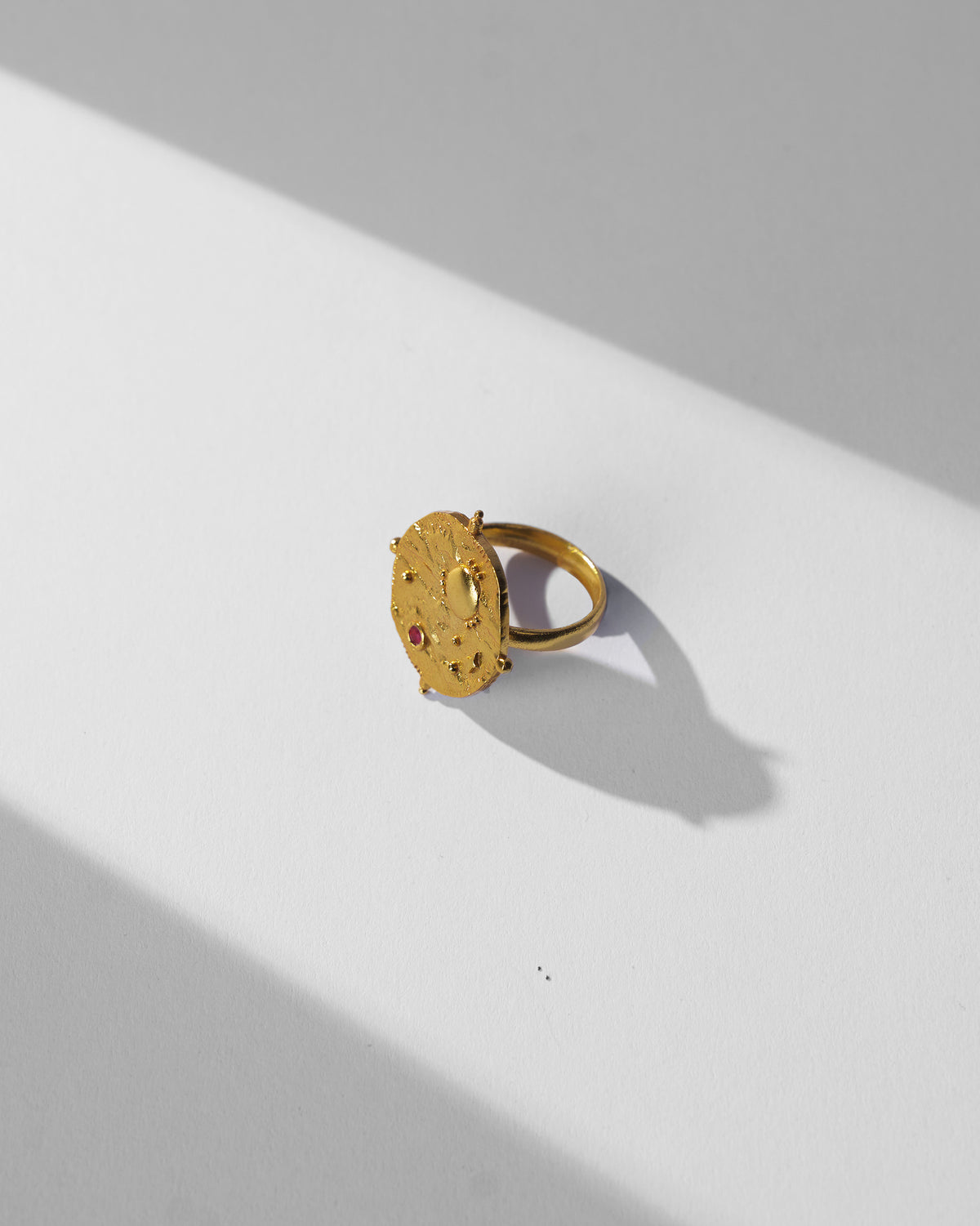 Gold Nebra ring showing hammered face and pink stone.