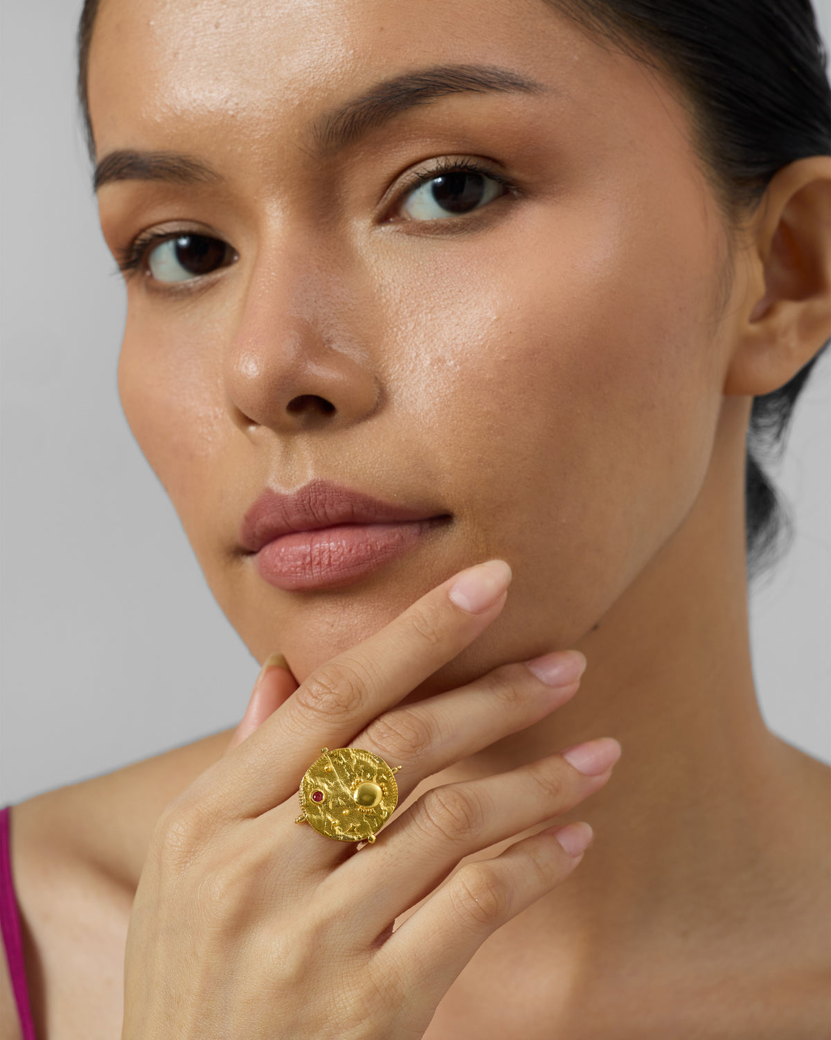 Person wearing a textured gold Nebra disc ring.