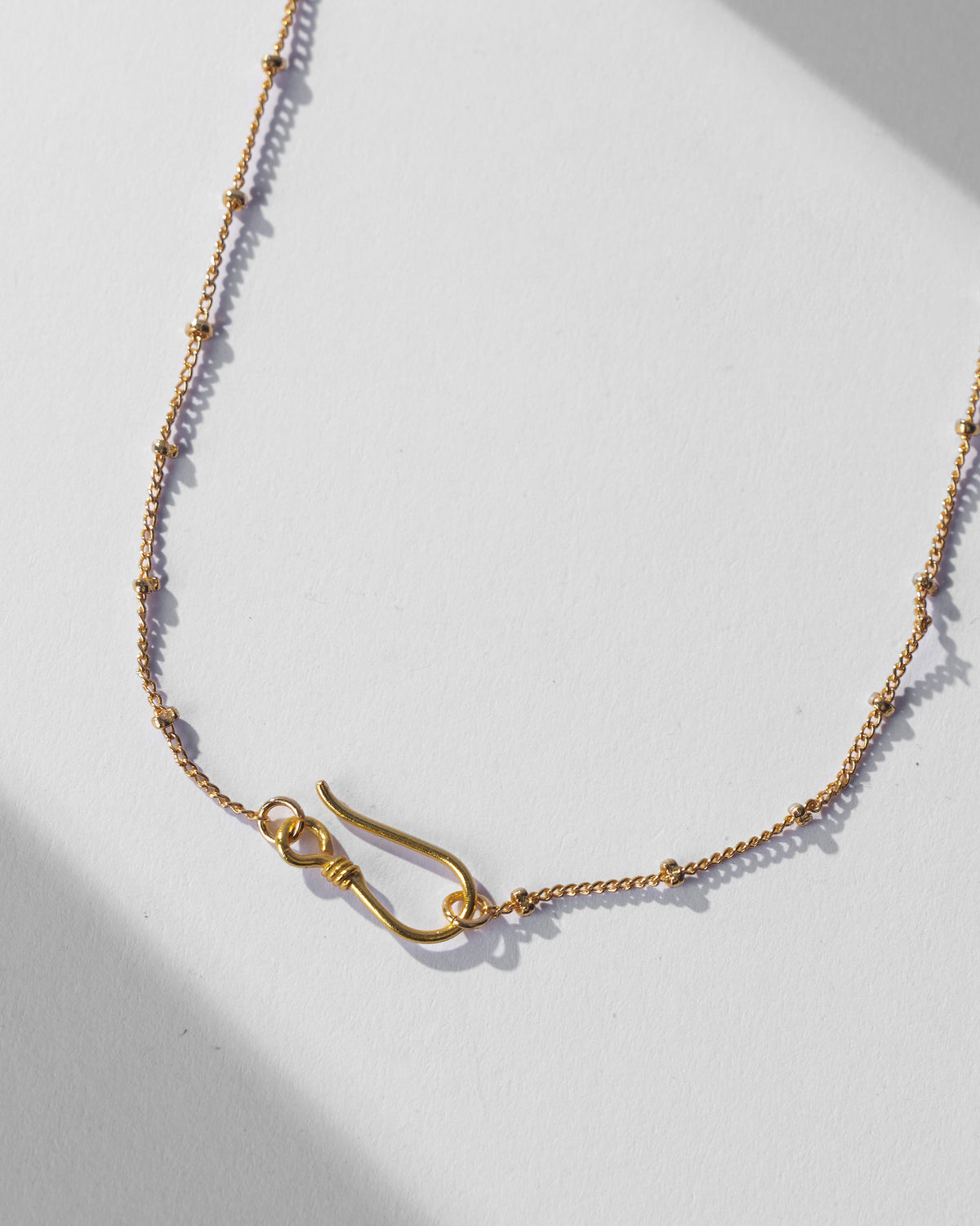 Close-up of the gold Saras necklace satellite chain and S-hook clasp.