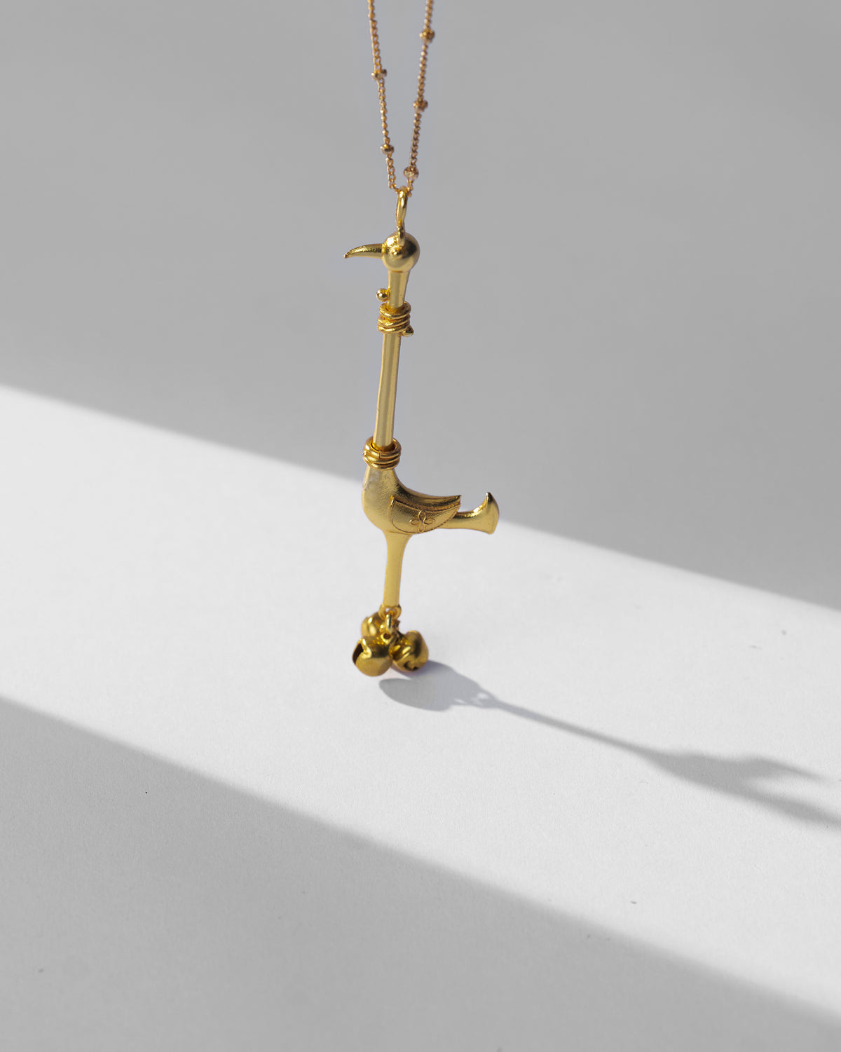 Gold Saras necklace hanging to show the long-necked bird pendant.