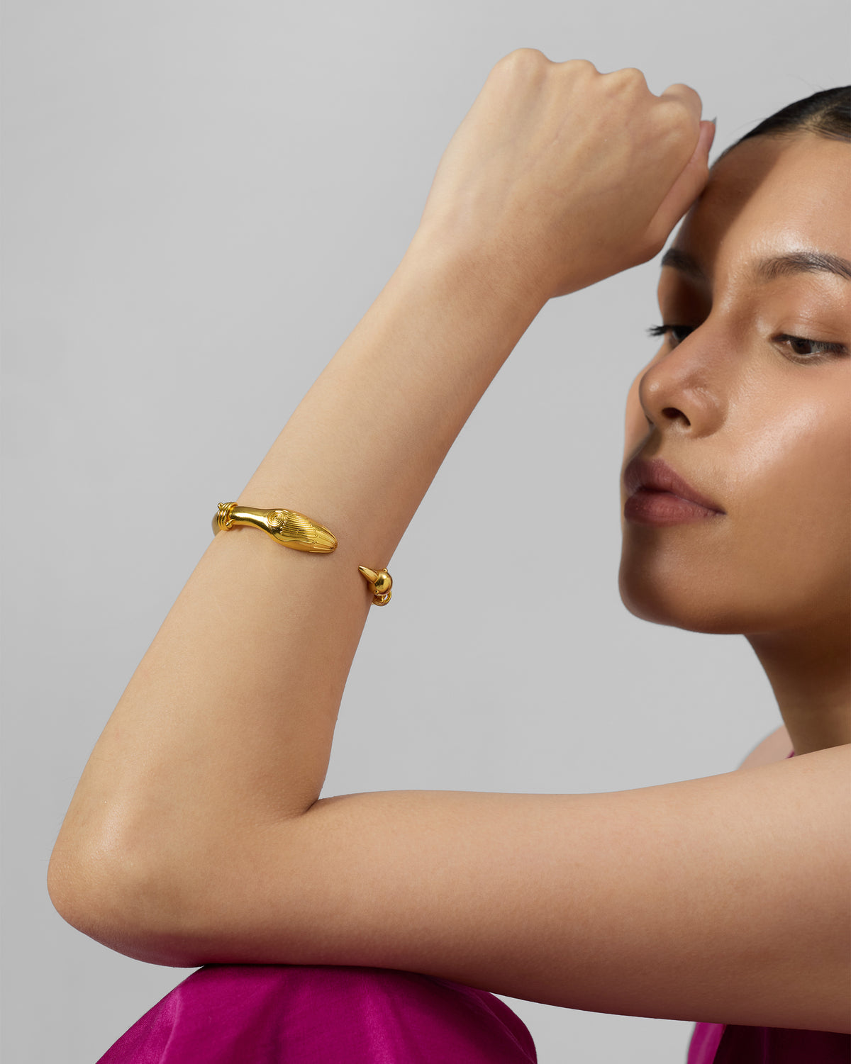 Person wearing a gold Saras bird-head cuff on the wrist.