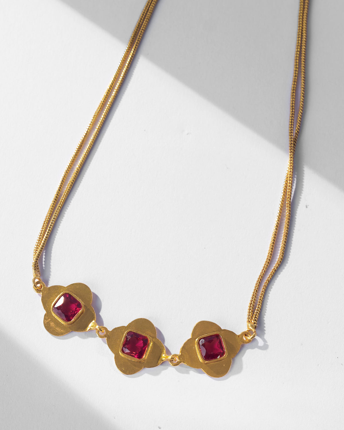 Close-up of Ahiliya choker with three pink glass quatrefoil motifs.