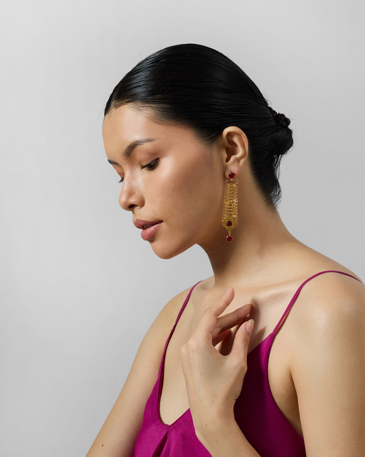 Side profile of long gold Ahiliya danglers with red glass on a person.