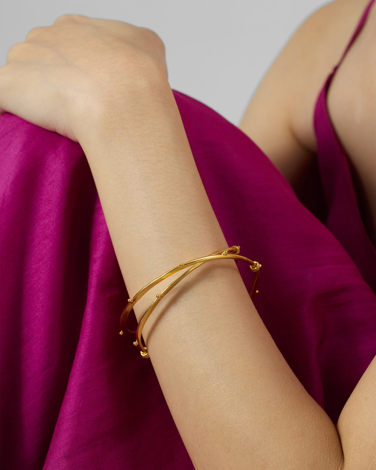 Gold Double Loop Bangle with bead accents worn on a wrist.
