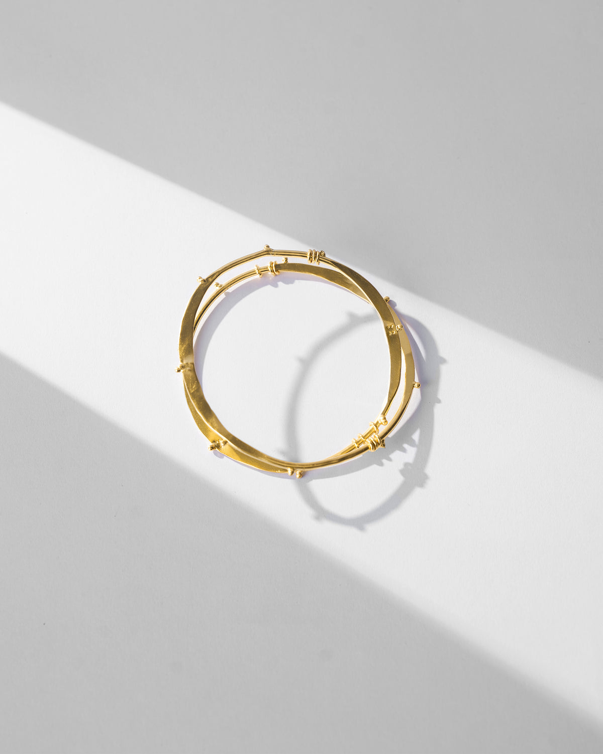 Gold Double Loop Bangle showing two thin circular bands with raised nodes.