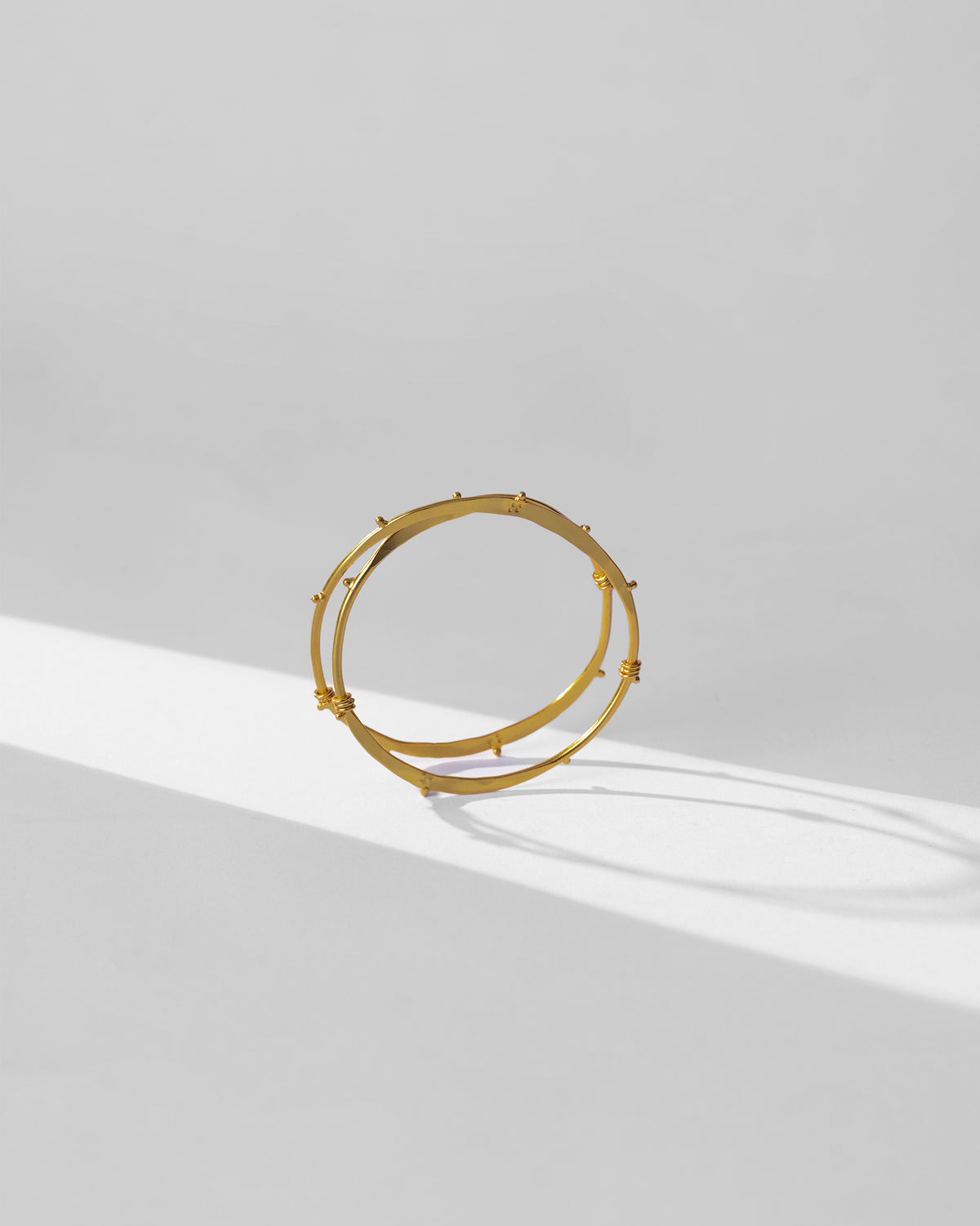 Gold Double Loop Bangle standing to show two parallel bands joined together.