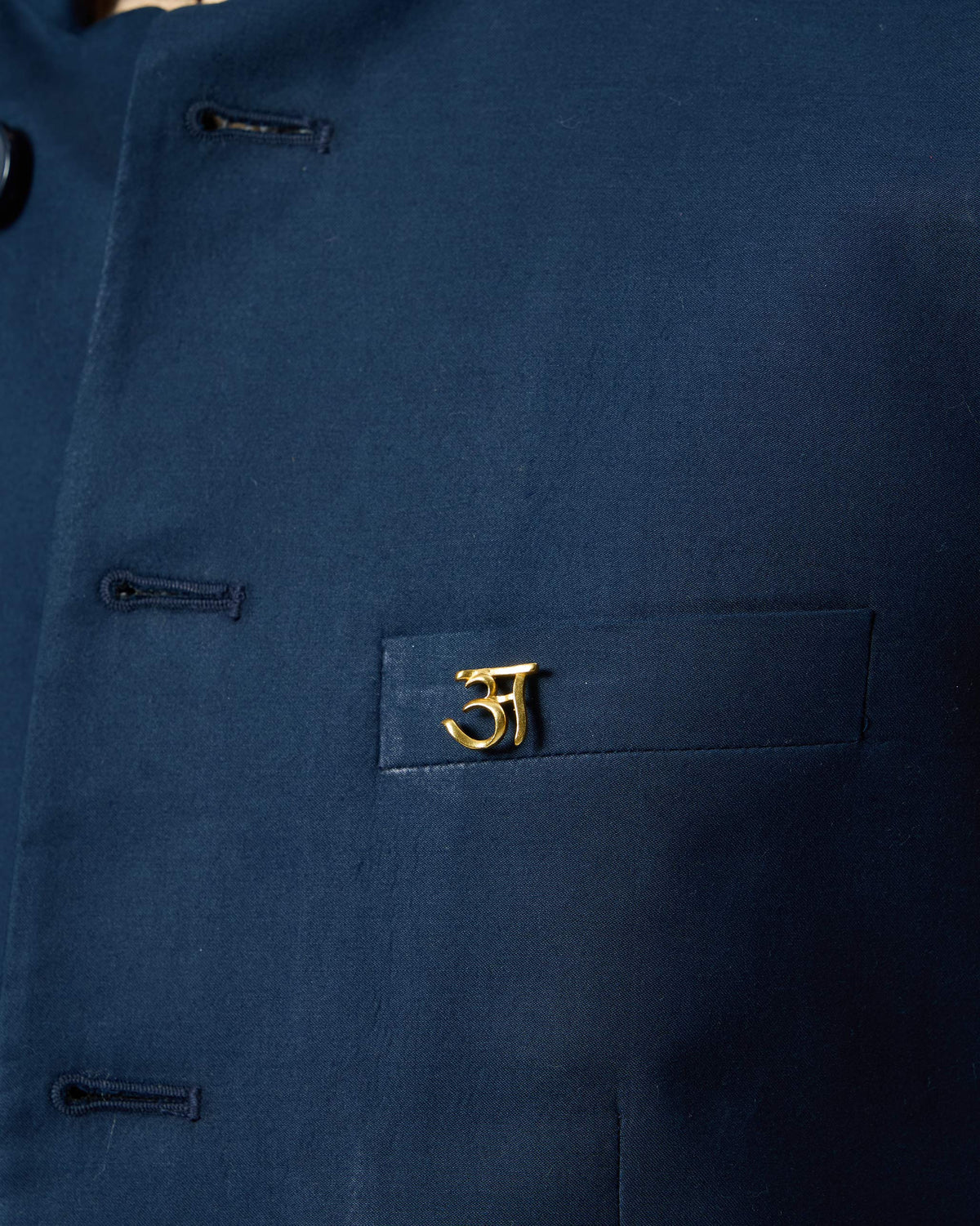 Gold Alphabet A Pin pinned to a navy jacket pocket.
